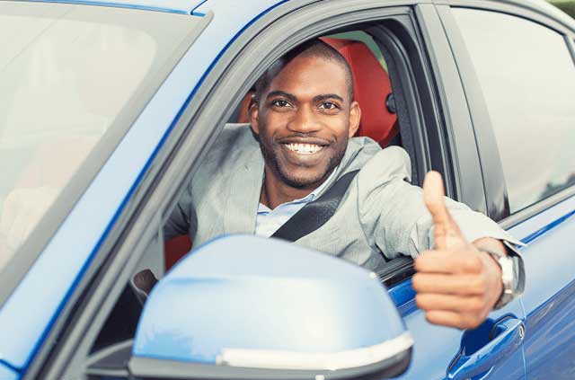 A happy chap gives a thumbs up out a car window.